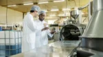 Two workers in factory looking over a tablet while learning on the job.