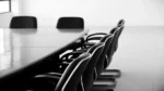 An office conference table with several empty chairs.