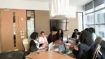 Group of African American women sitting at a conference table discussing the possibilities of online proctoring