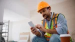 Construction worker onsite looking at his phone while taking an workplace safety online assessment