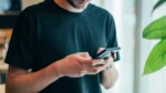 Man holding smartphone while taking a proctored online safety training test.