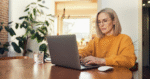 Woman working on laptop at home representing online exam proctoring and academic integrity in an AI-enabled learning environment.